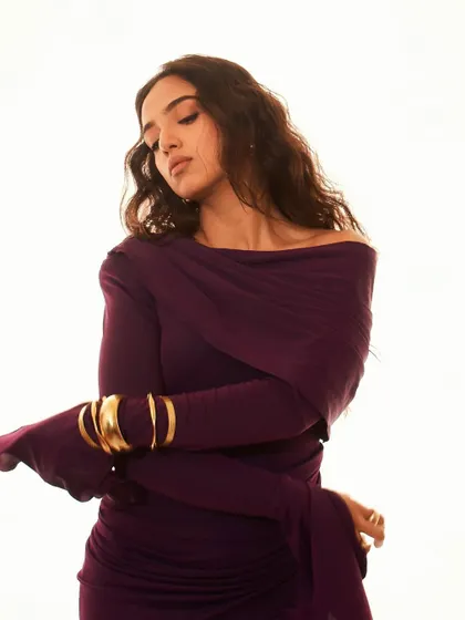 A shot focusing on the elegant draping of the purple gown and the statement gold cuff bracelet.