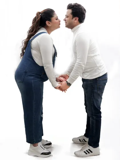 A playful and romantic pose between the expecting couple, holding hands and sharing a moment of fun before their little one arrives.