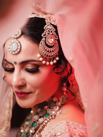 A close-up of one of our brides, capturing the dreamy, romantic look we created. This artistic shot highlights the detailed eye makeup, flawless skin finish, and the perfect placement of traditional jewelry, all essential for a timeless bridal portrait.