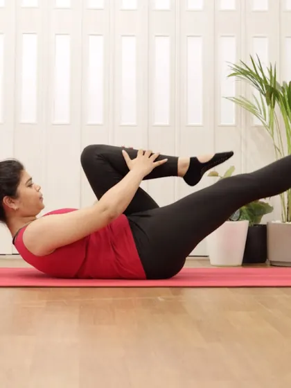A member performs a single-leg stretch, a fundamental Pilates exercise for building abdominal strength and endurance.