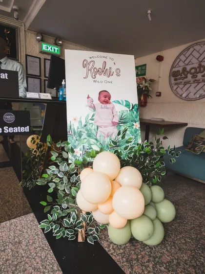 A personalized welcome sign for "Roohi's Wild One," decorated with soft green balloons and foliage, set a sweet and adventurous tone at the entrance.
