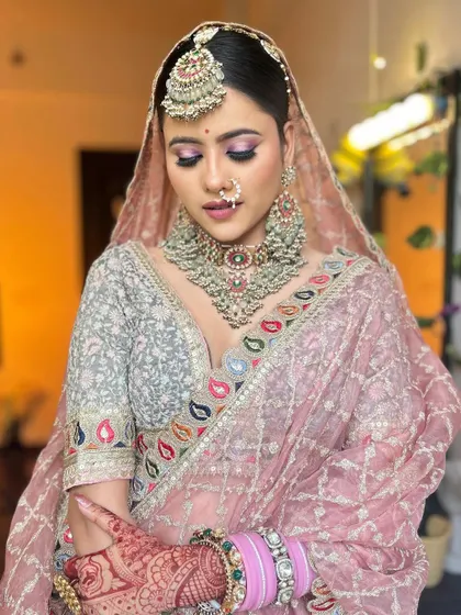 A close-up of the pastel pink lehenga look, focusing on the beautiful makeup and the intricate, heavy jewellery.