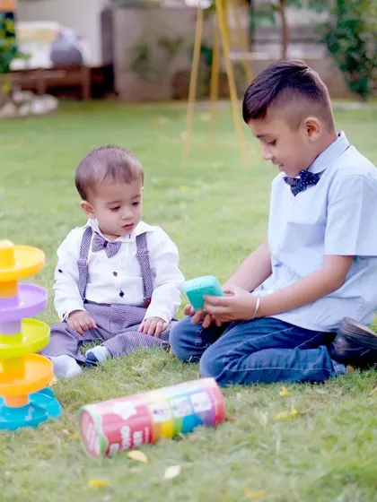 An older boy shares a toy with a toddler during a relaxed outdoor play session, a lovely example of sibling and friends photography.