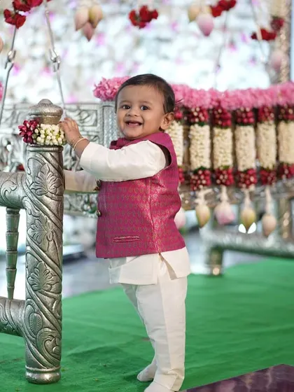 The happiest little client! For his naming ceremony, I designed this adorable white kurta set with a custom-fit pink brocade Nehru jacket to match his father's outfit.