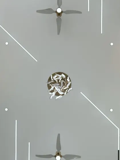 A view of a false ceiling with a unique, abstract lighting design and a sculptural chandelier. This shows how the "fifth wall" can be a work of art.