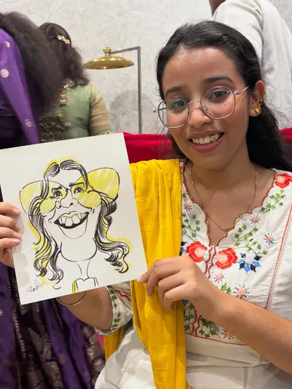A young guest with a bright smile, holding her equally cheerful caricature.
