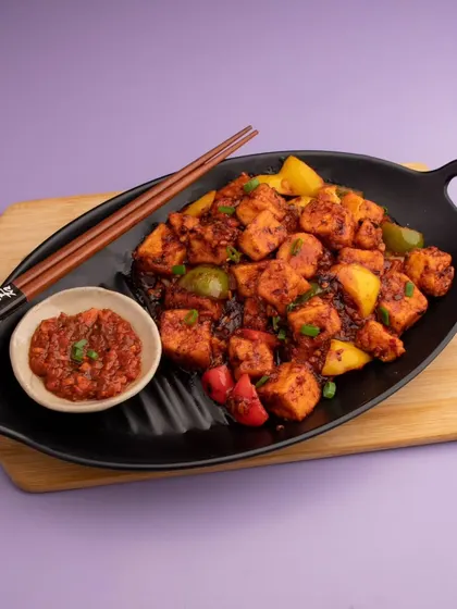 A shot of spicy paneer chilli, designed for a Zomato or Swiggy menu. The focus is on making the dish look vibrant and delicious, encouraging customers to click and order.