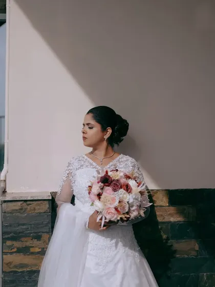 An artistic bridal portrait using light and shadow. The bride stands against a wall, creating a contemplative and elegant mood.