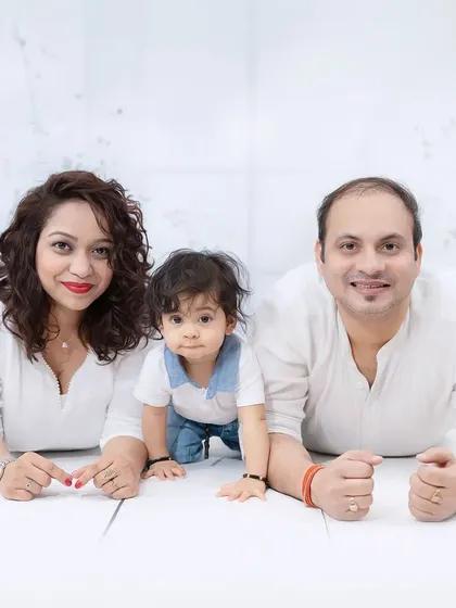 A fun family photo with parents and their baby lying on their stomachs, looking like they're ready to crawl together. A playful and unique portrait.
