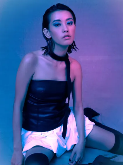 A seated pose that feels both relaxed and powerful, enhanced by the vibrant pink and blue lighting.