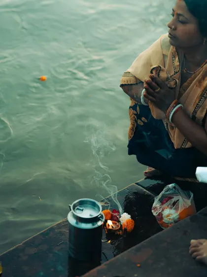A woman in prayer at the banks of the Ganga in Rishikesh. This is a quiet, documentary-style photo that captures a moment of personal faith and devotion.