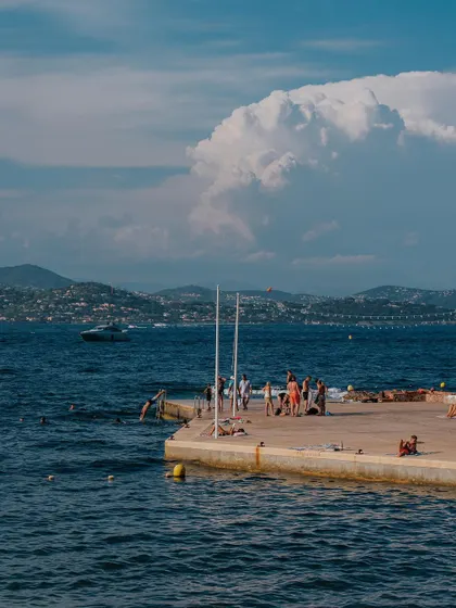 People enjoying a sunny day on a concrete pier in St. Tropez. Lifestyle shots of locals and tourists help to paint a picture of what it feels like to be there.