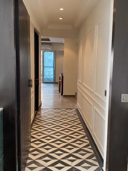 After: The same foyer transformed with striking black and white geometric flooring and classic white wall paneling.