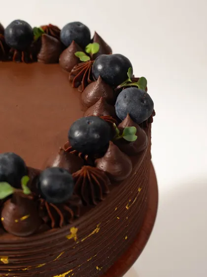 A close-up detail of the piped chocolate frosting and fresh blueberries on our Chocolate and Berry Cake.
