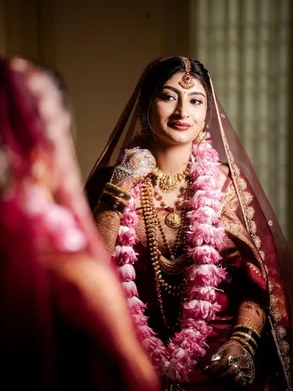 The bride looking at her reflection. Her makeup is glamorous and perfectly applied, making her feel confident and beautiful.