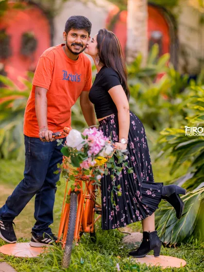 A sweet kiss on the cheek next to a bicycle. This candid moment is full of affection and captures the playful side of the couple's relationship.