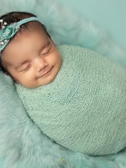 A heart-melting smile from a baby swaddled in a soft mint-green knit wrap. I use safe wrapping techniques to keep babies feeling secure and content, which often leads to these beautiful expressions.