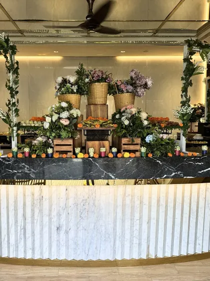 A stunning example of our farmers market theme, featuring a marble-topped counter filled with wicker baskets of fresh flowers and produce. This setup brings a rustic, organic, and vibrant feel to any corporate gathering.