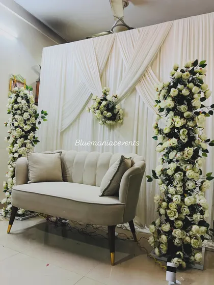 A wider shot of the home Roka setup, showing the two floral pillars framing the seating area. The clean white drapes create a perfect canvas that makes the floral arrangements pop.