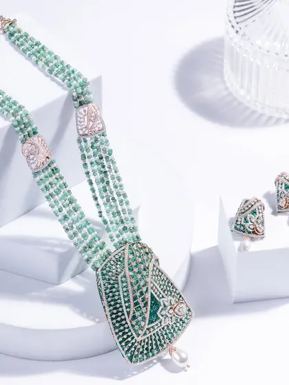 The complete Bandhani-inspired set. A multi-strand emerald bead necklace with a statement diamond pendant, perfectly paired with matching earrings.