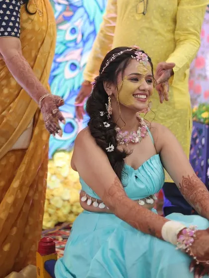 A candid moment of joy during the Haldi ceremony. Her braided hairstyle and floral jewelry are perfect for the playful and happy occasion.