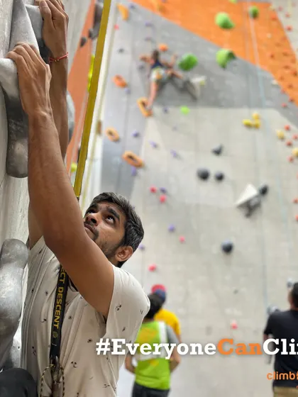 Our motto in action: #EveryoneCanClimb. A climber focuses on his ascent while others climb in the background, showing our gym is a space for all.