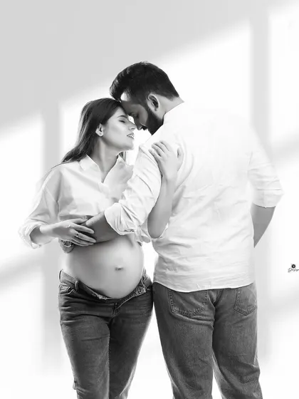 An intimate black and white portrait of a couple in a gentle embrace. The casual outfits and soft lighting create a timeless and authentic image of their connection.
