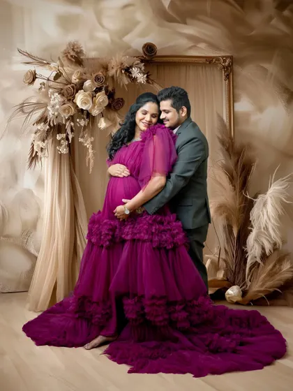 An intimate embrace between the couple. This pose highlights their close bond and the shared excitement of their journey to parenthood, framed by the beautiful gown and backdrop.