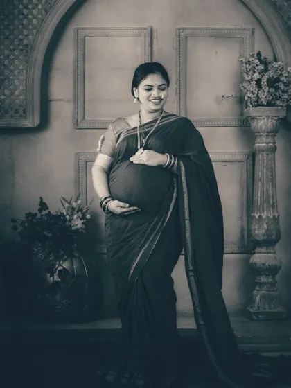 In this solo black and white portrait, the focus is on the graceful silhouette of the mother-to-be. The dramatic lighting carves out her form against the vintage backdrop, creating a truly artistic image.