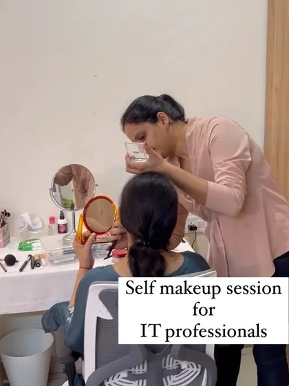 An IT professional learning makeup in an offline session. I am explaining a concept while she observes in the mirror before trying it herself.