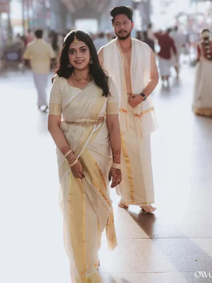 A beautiful, sunlit portrait of the bride walking in the temple, with her groom following behind.