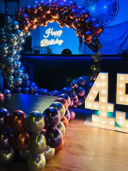 A 45th birthday party at a club, featuring a chrome balloon arch and large marquee numbers.