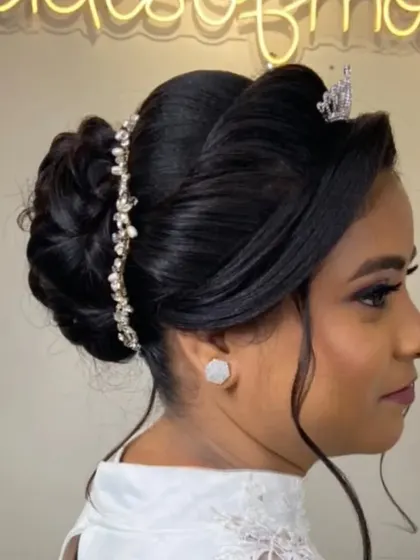 A sophisticated updo for a Christian bride, featuring a tiara and a decorative hair vine wrapped around the bun.