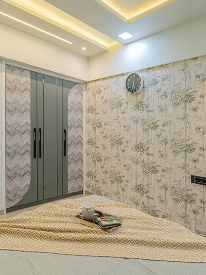 The wardrobe in this bedroom features a fluted door design that matches the room's overall theme. The statement wallpaper with a bamboo motif adds a natural, calming element.