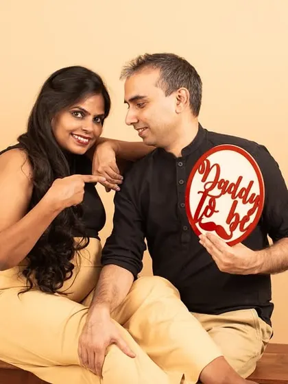 A playful studio shot where the mom-to-be points to her partner, who holds a 'Daddy to be' sign. It’s a fun way to announce the exciting news.
