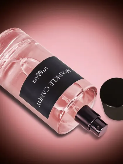 This image of the 'Sparkle Candy' perfume uses a gradient background and soft lighting. The focus is entirely on the bottle, highlighting its clean design and pink hue.