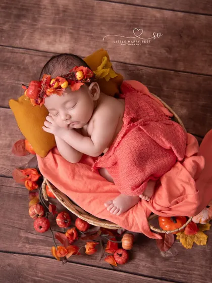 Autumn vibes for this little princess. The orange wrap and matching floral headband, surrounded by pumpkins and leaves, create a beautiful and warm seasonal portrait.