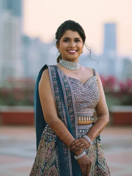 A portrait of the happy bride. Her makeup is natural and radiant, with a focus on clean skin and a bright smile, complementing her detailed reception lehenga.