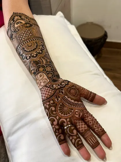 A full-arm bridal mehndi design with incredible detail. It combines florals, paisleys, and geometric patterns to create a truly breathtaking look for the bride's special day.