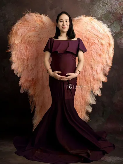 A creative portrait featuring beautiful, large angel wings. This prop adds a touch of fantasy and magic to the maternity session.