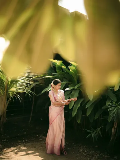 A portrait of the bride seen through a soft-focus foreground of leaves, creating a dreamy, ethereal effect.