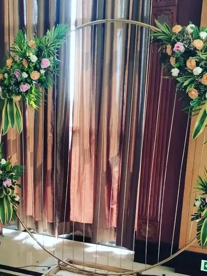 A modern circular ring prop decorated with pastel roses and green leaves. This kind of piece works well as a photo backdrop or as a decorative element behind the main stage.