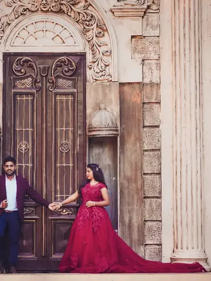 A romantic shot of the couple holding hands, showcasing the beautiful trail of the red gown.