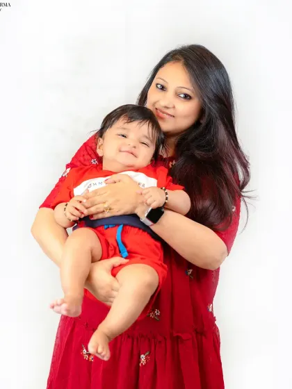A mother holds her smiling baby close, both radiating warmth and happiness. This portrait, set against a simple white background, highlights their special connection.