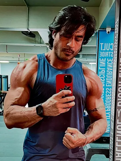 Flexing to show the arm and shoulder definition that comes from a hybrid training approach. We build both size and separation for a complete look.
