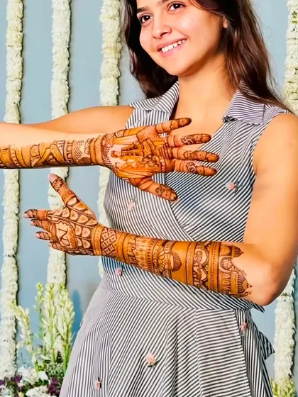 A happy bride showing both her palms, one with her initial and the other with her partner's.