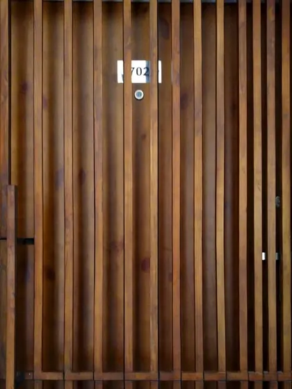 A close-up of the entrance door for the Gurgaon residence, detailed with vertical wooden slats. This custom fixture introduces the design language of the interior, where wood is used to create texture, rhythm, and spatial division.