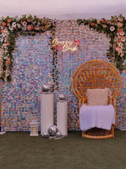 This iridescent sequin backdrop adds a touch of glamour to any baby shower. Paired with a peacock chair and floral garlands, it creates a shimmering and festive photo corner for the celebration.
