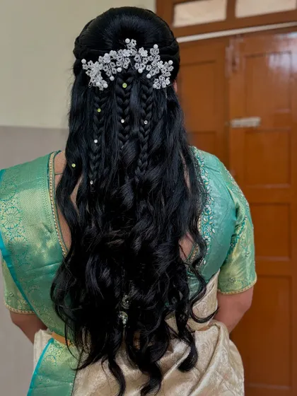 This intricate half-up hairstyle for Rakshitha's reception combines braids, curls, and delicate crystal accessories. It’s a style that feels both traditional and modern, keeping the hair off her face while showcasing its length.