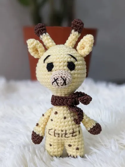 This little crochet giraffe, named 'Chittu', has a sweet expression and a cozy brown scarf. Personalizing toys with names makes them one of a kind.